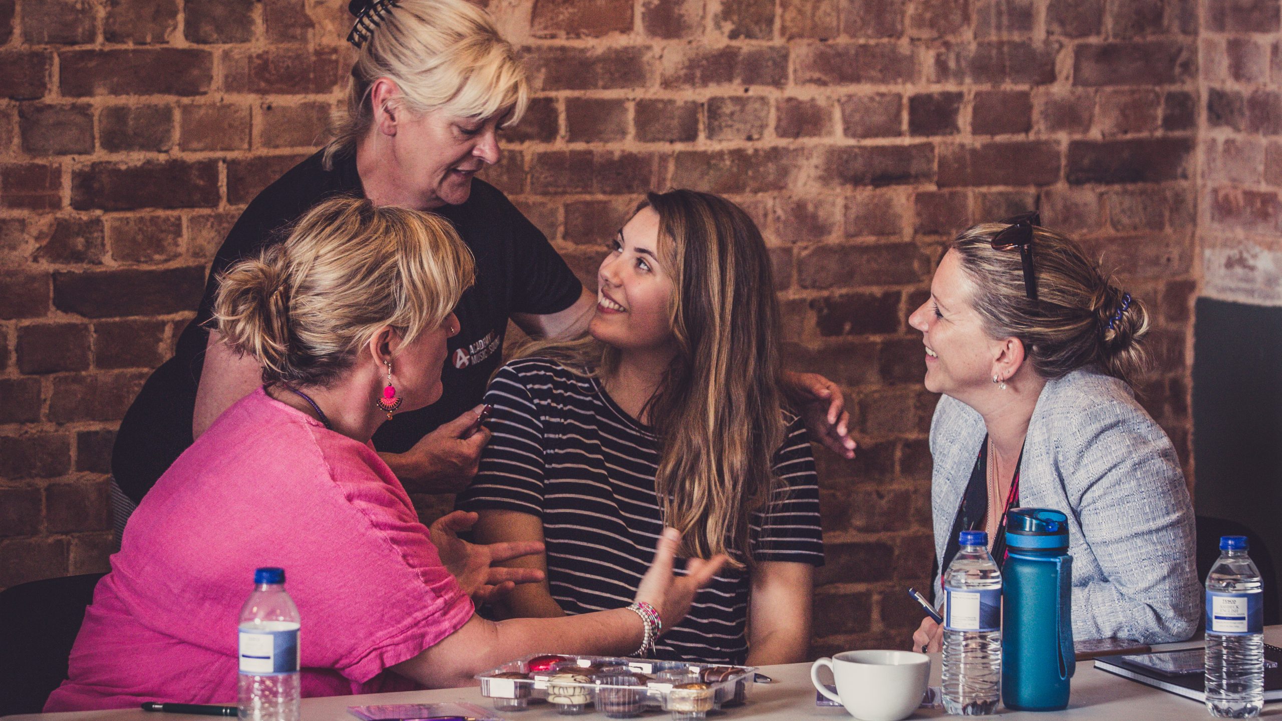 Four women sit around a table discussing an idea