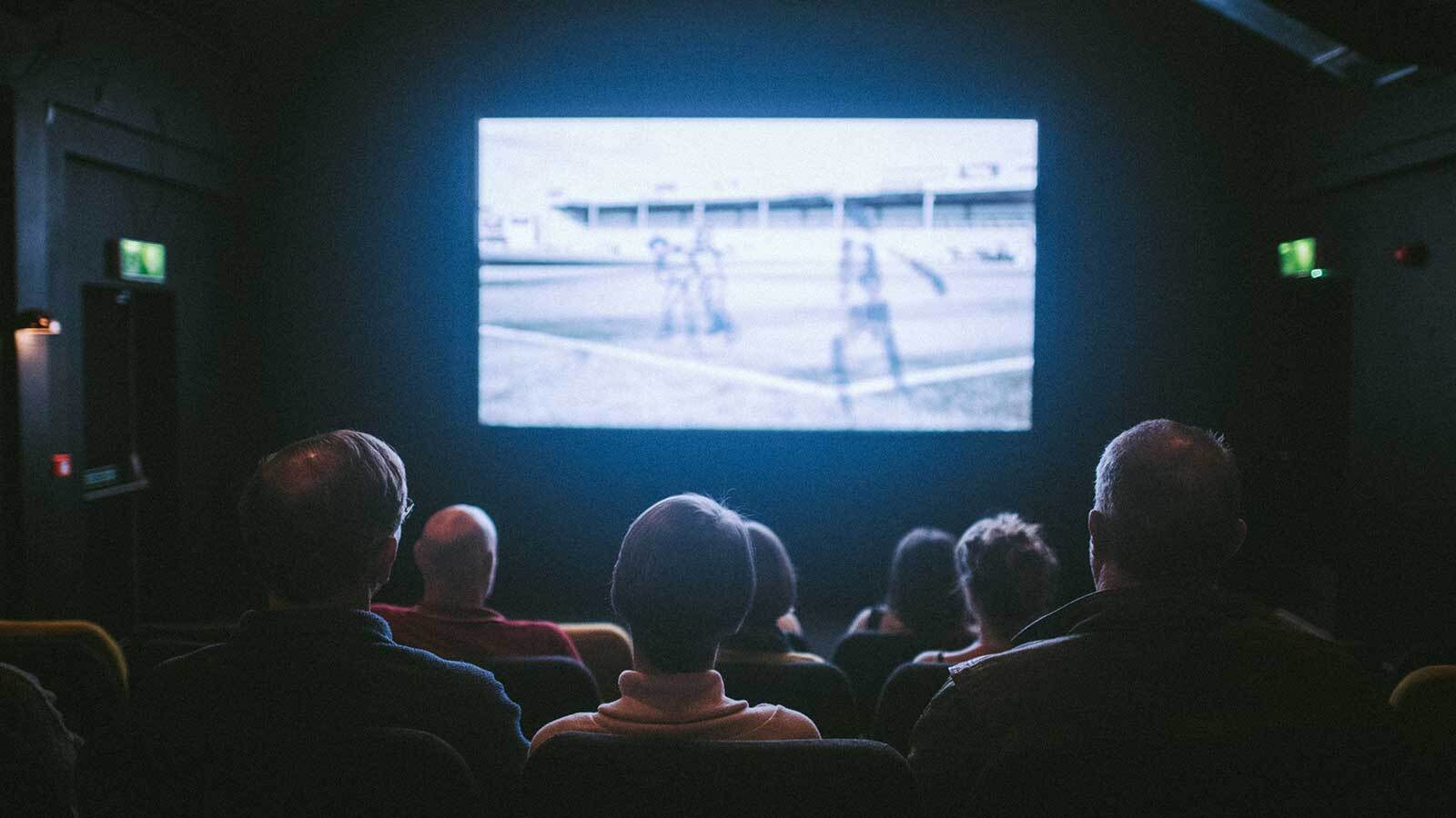 The backs of peoples heads as they watch an animated film in the cinema